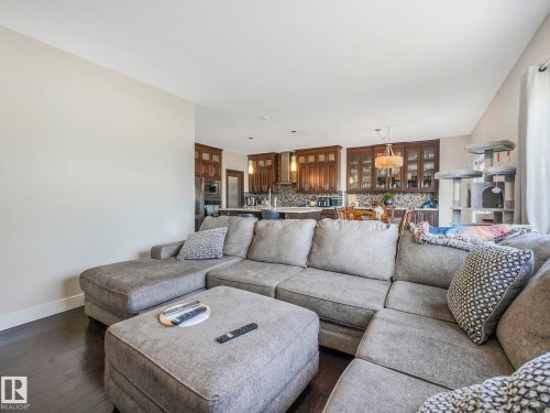 Living area featuring dark hardwood floors and an open concept view of the kitchen with dark wood cabinetry and a decorative backsplash - 3910 49 Avenue, Beaumont, AB - Indoor Photo Showing Living Room