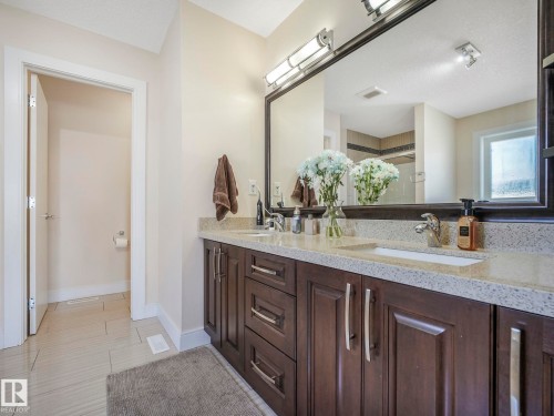 The bathroom features a double vanity with two rectangular sinks, a light-colored speckled countertop, and dark wood cabinetry with silver hardware - 3910 49 Avenue, Beaumont, AB - Indoor Photo Showing Bathroom