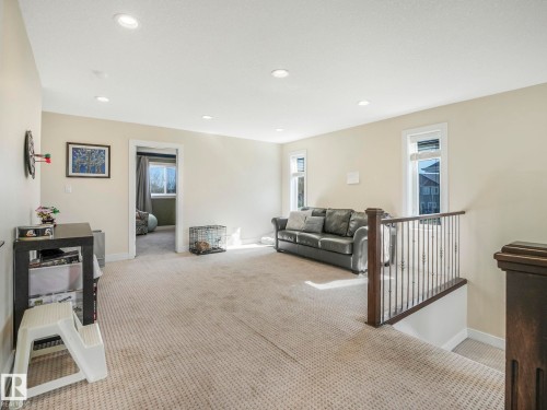 This property features a versatile open area with light-colored carpeting, recessed lighting, and a dark wood and metal railing - 3910 49 Avenue, Beaumont, AB - Indoor