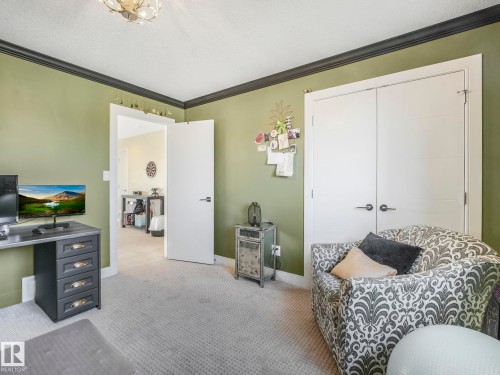 This room features soft green walls, a light-colored carpet, and white doors with dark hardware - 3910 49 Avenue, Beaumont, AB - Indoor Photo Showing Bedroom