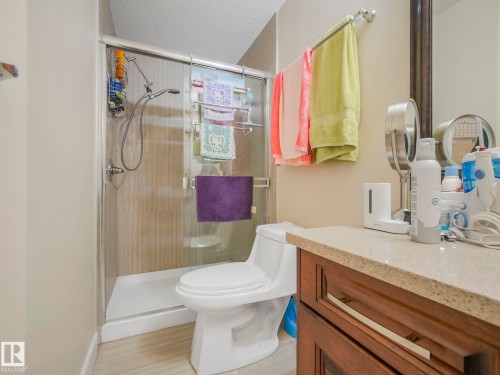 The bathroom features a shower with a glass enclosure, a toilet, and a vanity with a light-colored countertop and dark wood cabinetry - 3910 49 Avenue, Beaumont, AB - Indoor Photo Showing Bathroom