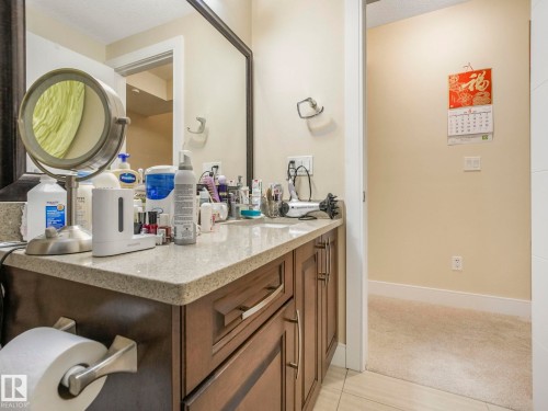 Bathroom vanity with a speckled countertop, brown cabinetry, and a large mirror - 3910 49 Avenue, Beaumont, AB - Indoor Photo Showing Bathroom