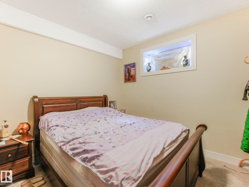 This bedroom features neutral-toned walls, a recessed light fixture, and a window with a display shelf - 3910 49 Avenue, Beaumont, AB - Indoor Photo Showing Bedroom