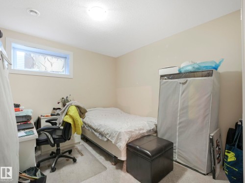 This room features light-colored walls and carpeting, a window, and a ceiling light fixture - 3910 49 Avenue, Beaumont, AB - Indoor Photo Showing Bedroom