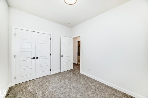 This room features white walls, gray carpeting, and white doors with black hardware - 341 Roberts Wynd, Leduc, AB - Indoor Photo Showing Other Room