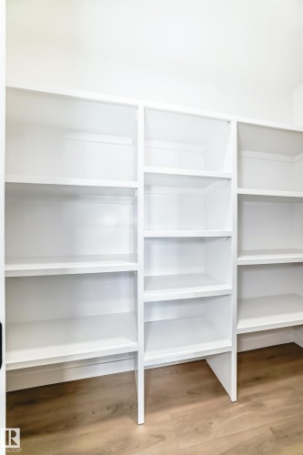 The property features extensive built-in white shelving with a light wood-style floor - 341 Roberts Wynd, Leduc, AB - Indoor With Storage