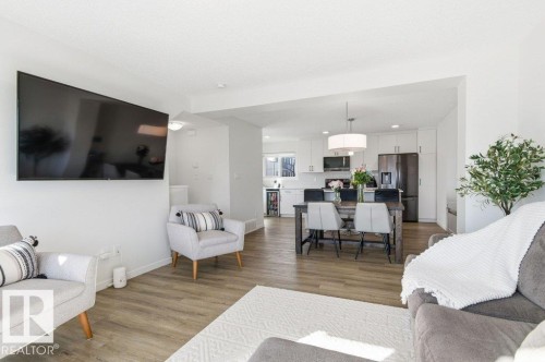 Living area featuring light wood-style flooring, a white area rug, and an open concept view into the kitchen and dining area - 49 850 Secord Boulevard, Edmonton, AB - Indoor Photo Showing Living Room