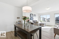 The open concept living area features light-colored flooring, white walls, and ample natural light from large windows - 