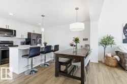 The property features an open-concept living space with light-toned flooring, a kitchen island with seating, white cabinetry, and stainless steel appliances - 