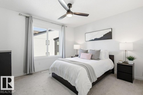This room features light-colored walls and carpeting, a window with curtains, and a ceiling fan with integrated lighting - 49 850 Secord Boulevard, Edmonton, AB - Indoor Photo Showing Bedroom