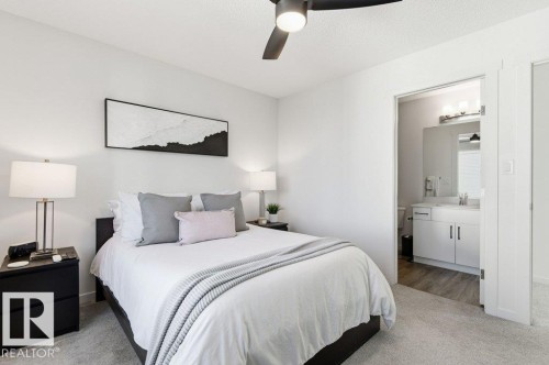This bedroom features light-colored walls and carpeting, a ceiling fan with integrated lighting, and an entryway to a bathroom - 49 850 Secord Boulevard, Edmonton, AB - Indoor Photo Showing Bedroom