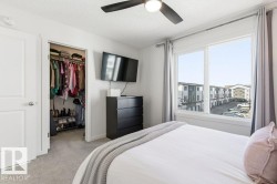 Inviting bedroom with light gray carpeting, a window offering views of the surrounding community, and a ceiling fan - 