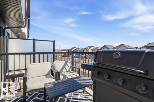 Enjoy outdoor living on the balcony, featuring black railings, privacy screens, and a patterned outdoor rug - 49 850 Secord Boulevard, Edmonton, AB - Outdoor With Exterior