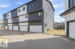 The property features a modern exterior with dark gray and white siding, individual garages, and a paved driveway - 