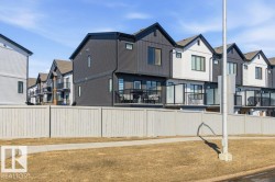 The property features modern exterior design with contrasting dark and light siding, individual balconies with glass railings, and a private fenced yard - 