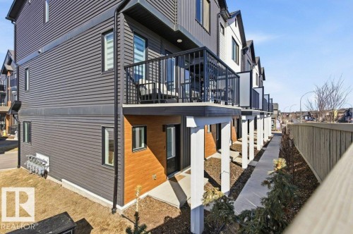 The property features a balcony with black railings, a dark gray siding exterior, and a brown wood accent panel - 49 850 Secord Boulevard, Edmonton, AB - Outdoor