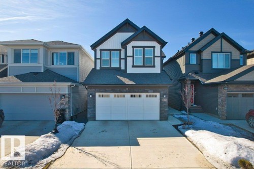 The property features a two-story design with a prominent white and dark facade, complemented by stone accents on the lower level - 21003 131 Avenue, Edmonton, AB - Outdoor With Facade