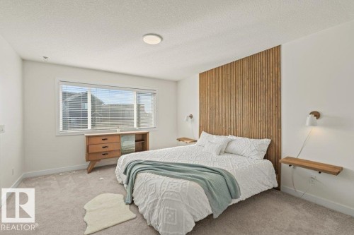 This bedroom features light-colored carpet flooring, a window with blinds, and a distinctive wooden slat wall accent behind the bed - 21003 131 Avenue, Edmonton, AB - Indoor Photo Showing Bedroom