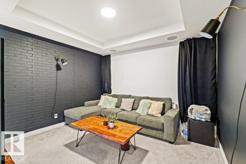 Living area featuring a dark brick accent wall, light-colored carpeting, and recessed lighting - 21003 131 Avenue, Edmonton, AB - Indoor Photo Showing Living Room