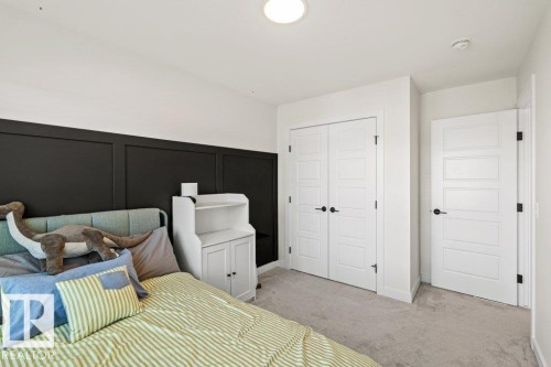 This room features light gray carpeting, a dark accent wall with paneling, and white interior doors with black hardware - 21003 131 Avenue, Edmonton, AB - Indoor Photo Showing Bedroom