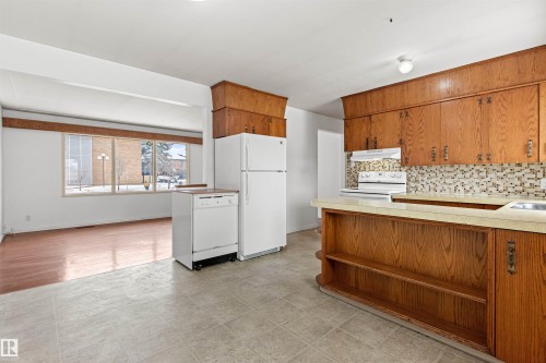 The kitchen features wood cabinetry, a tiled backsplash, and white appliances - 8608 156 Street, Edmonton, AB - Indoor Photo Showing Kitchen