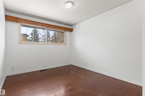 The room features white walls, dark hardwood flooring, and a large window providing views of trees - 8608 156 Street, Edmonton, AB - Indoor Photo Showing Other Room