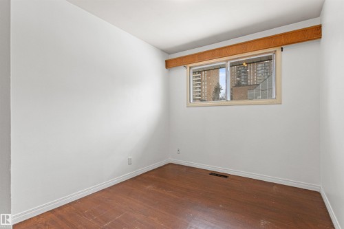 This room features hardwood floors, white walls, and a window with a wooden frame providing natural light - 8608 156 Street, Edmonton, AB - Indoor Photo Showing Other Room