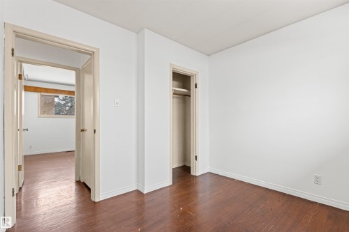 This room features rich brown flooring, white walls, and a convenient built-in closet with a hanging rod - 8608 156 Street, Edmonton, AB - Indoor Photo Showing Other Room