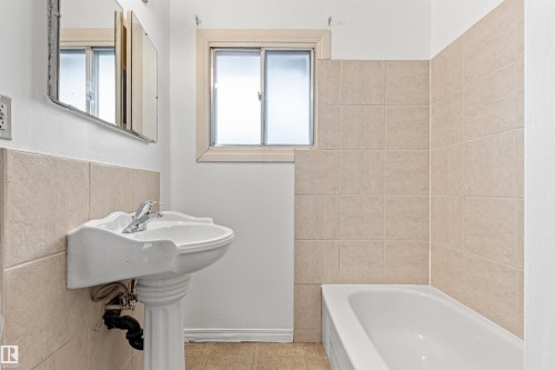 Bathroom featuring a white pedestal sink, a bathtub, and tiled walls around the bath and sink area - 8608 156 Street, Edmonton, AB - Indoor Photo Showing Bathroom