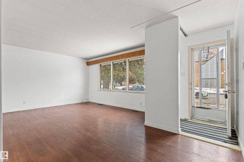 The property features hardwood floors, white walls, and a large window with wooden trim - 8608 156 Street, Edmonton, AB - Indoor Photo Showing Other Room