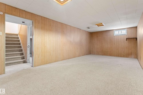 An expansive room featuring carpeted flooring, wood-paneled walls, and a recessed ceiling light - 8608 156 Street, Edmonton, AB - Indoor Photo Showing Basement