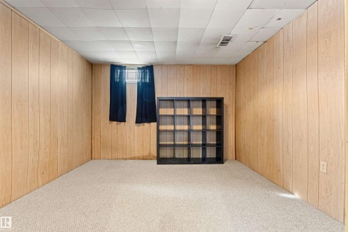 This room features light-colored carpet, wood paneling on the walls, and a window with dark curtains - 8608 156 Street, Edmonton, AB - Indoor Photo Showing Other Room
