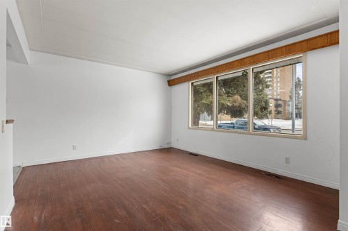 Spacious living area featuring hardwood flooring and large windows, providing views of the neighborhood - 8608 156 Street, Edmonton, AB - Indoor Photo Showing Other Room