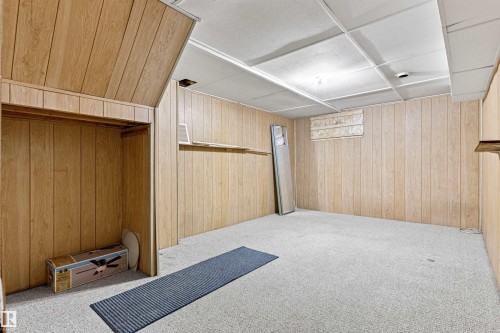 Room featuring wood paneling on the walls, a drop ceiling, and light-colored carpeting - 8608 156 Street, Edmonton, AB - Indoor