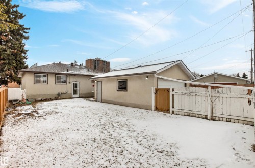 The property features a detached garage with a white garage door and a rear yard with a wooden fence - 8608 156 Street, Edmonton, AB - Outdoor