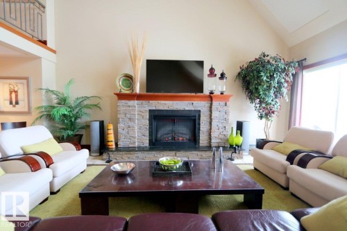 Carpeted living area with a stone fireplace and vaulted ceiling - 1402 9707 105 Street, Edmonton, AB - Indoor Photo Showing Living Room With Fireplace
