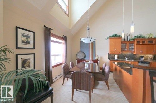 Dining area featuring a high ceiling, light colored carpet, and baseboard heating - 1402 9707 105 Street, Edmonton, AB - Indoor With Fireplace