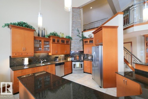 Kitchen with glass insert cabinets, a high ceiling, dark stone countertops, stainless steel appliances, and light tile patterned floors - 1402 9707 105 Street, Edmonton, AB - Indoor Photo Showing Kitchen