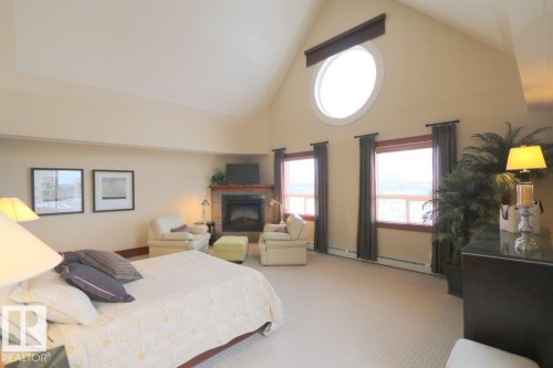 Carpeted bedroom featuring high vaulted ceiling, a fireplace, and a baseboard heating unit - 1402 9707 105 Street, Edmonton, AB - Indoor Photo Showing Bedroom With Fireplace