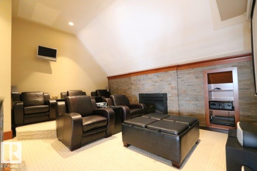 Home theater room featuring a stone fireplace, recessed lighting, vaulted ceiling, and light colored carpet - 1402 9707 105 Street, Edmonton, AB - Indoor With Fireplace