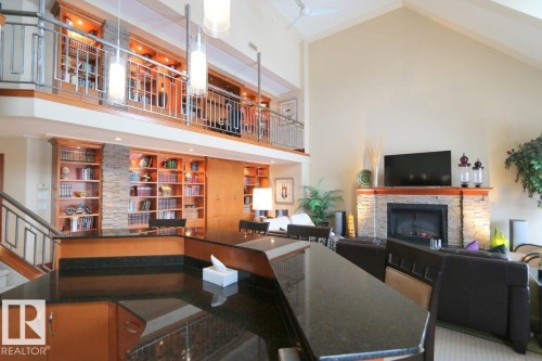 Bar area featuring high vaulted ceiling, a fireplace, and dark stone countertops - 1402 9707 105 Street, Edmonton, AB - Indoor With Fireplace