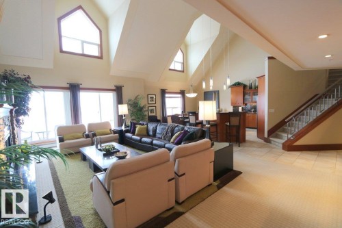 Living room with high vaulted ceiling, stairway, light carpet, and a fireplace - 1402 9707 105 Street, Edmonton, AB - Indoor Photo Showing Living Room