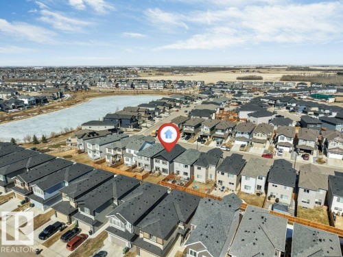 Aerial view showcasing the property within a residential development, featuring surrounding properties with dark-colored roofs and a visible body of water - 452 Roberts Crescent, Leduc, AB - Outdoor With View