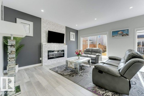 The living area features light-toned flooring, a fireplace with a tiled surround, and recessed lighting - 452 Roberts Crescent, Leduc, AB - Indoor Photo Showing Living Room With Fireplace