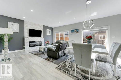 The living area features light-colored flooring, a fireplace with a tiled surround, and a sliding glass door leading to the exterior - 452 Roberts Crescent, Leduc, AB - Indoor With Fireplace