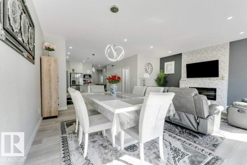 The property features an open-concept living area with light-colored flooring, a modern chandelier, and recessed lighting - 452 Roberts Crescent, Leduc, AB - Indoor Photo Showing Dining Room With Fireplace