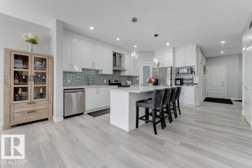 Contemporary kitchen featuring light-colored flooring, white cabinetry, stainless steel appliances, and a central island with seating - 452 Roberts Crescent, Leduc, AB - Indoor Photo Showing Kitchen With Upgraded Kitchen