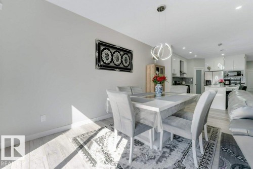 The property features light-toned flooring throughout, a modern light fixture, and a kitchen with stainless steel appliances - 452 Roberts Crescent, Leduc, AB - Indoor Photo Showing Dining Room