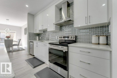 The kitchen features white cabinetry, a tiled backsplash, and stainless steel appliances - 452 Roberts Crescent, Leduc, AB - Indoor Photo Showing Kitchen With Upgraded Kitchen
