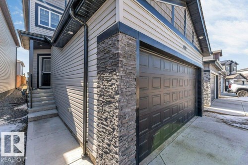 The property features a dark-colored garage door, light-colored siding, and stacked stone accents - 452 Roberts Crescent, Leduc, AB - Outdoor